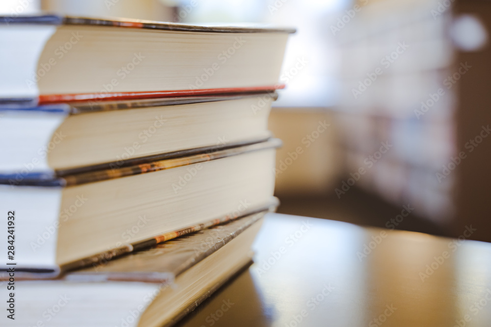 Book in library with old open textbook, stack piles of literature text archive on reading desk, and aisle of bookshelves in school study class room background for academic education learning concept Book in library with old open textbook, stack piles of literature text archive on reading desk, and aisle of bookshelves in school study class room background for academic education learning concept