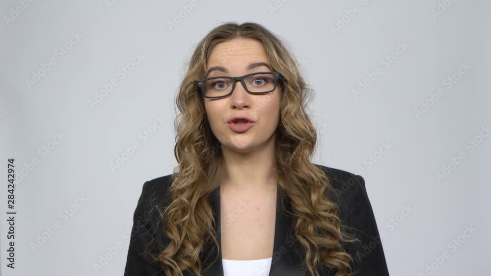 Businesswoman is reporting and tells a lot of interesting news against grey background Businesswoman is reporting and tells a lot of interesting news against grey background