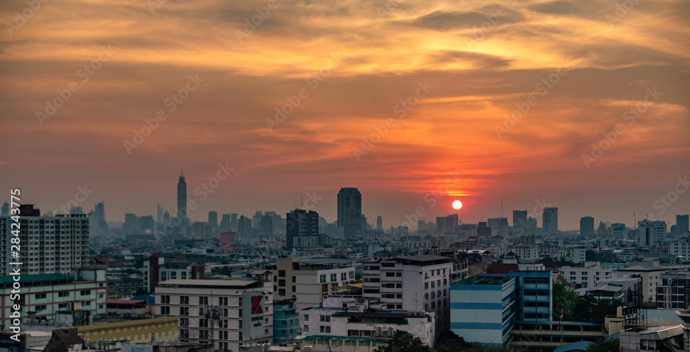 Obraz premium Bangkok city with a beautiful sunset over the skyline with orange skies, buildings and clouds.