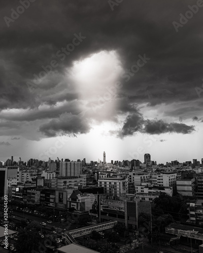 Bangkok city with dramatic cloud storm overpopulated buildings with sunlight beaming through clouds.