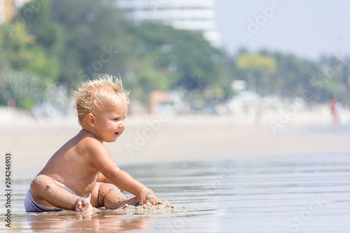 baby plays in water on a sea shore in a sunny weater in summer