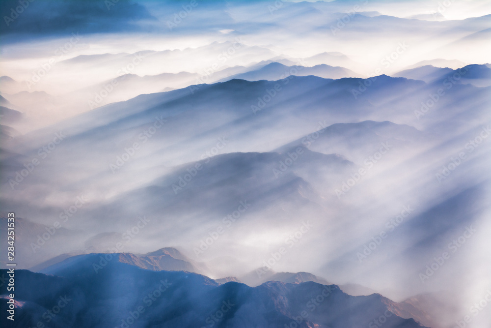 clouds over the Himalayan mountain range with streaks of sun rays