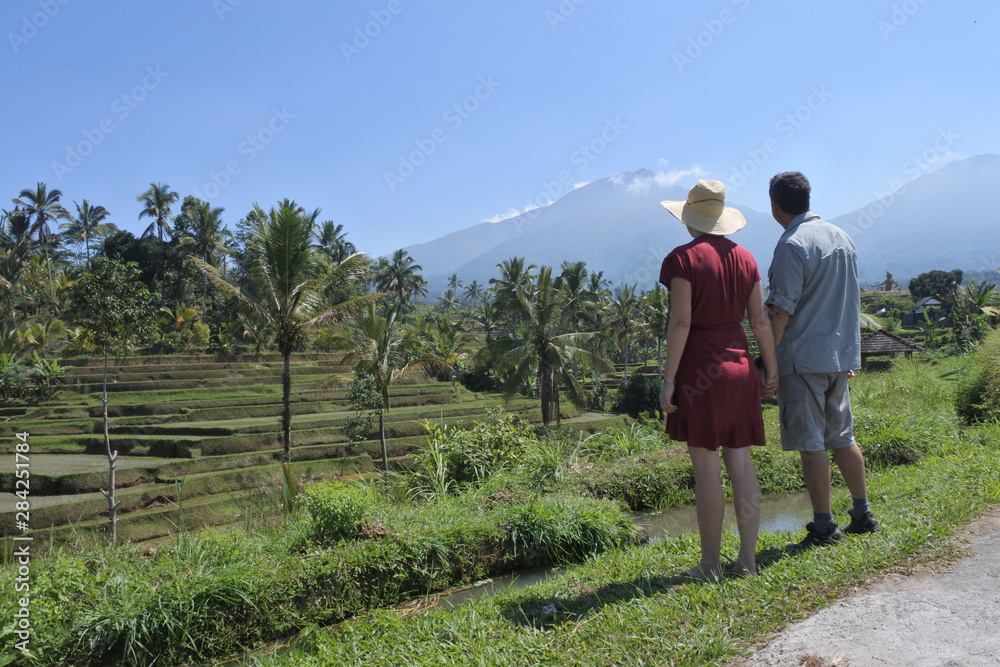 Tourist couple looking at the landscape view of rice fields in Jatiluwih rice terraces Bali Indonesia