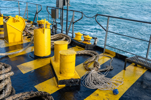 The deck of the ferry boat along with the a thick mooring rope and blue sea water wave, Thailand. Close up