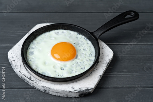 fried eggs in cast iron pan on white wooden stand.