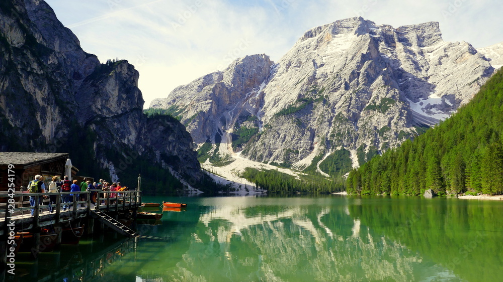 malerischer Blick auf Pragser Wildsee in Südtirol mit hohen Bergen und Touristen bei Ruderbooten