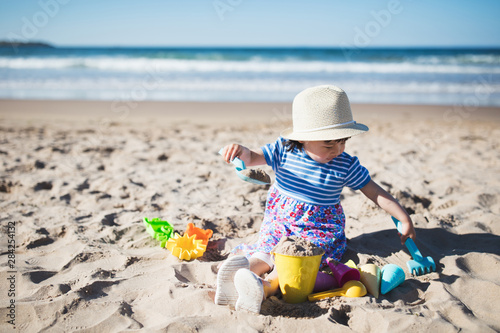 Canvas Print toddler girl playing at summer sand beach,Northern Ireland