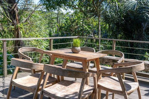 Wooden table and chairs in empty tropical cafe next to rice terraces in island Bali, Indonesia