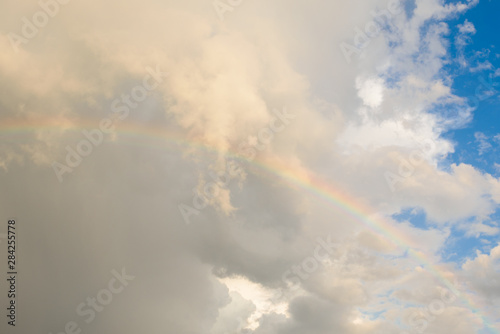 Bright colored rainbow amid blue skies after rain on warm summer day