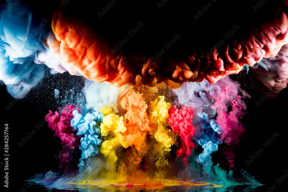Colorful rainbow paint drops from above mixing in water. Ink swirling underwater