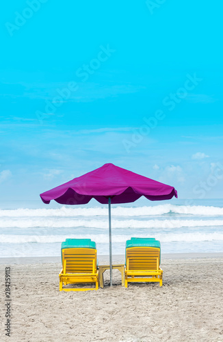 Purple Beach Umbrella With Yellow Lazy Wooden Chair on The Bali Beach During Summer Vacation