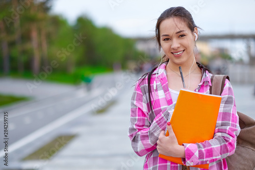 Smiling Asian Female Student with Folders and backpack in green summer park. education, campus and teenage concept