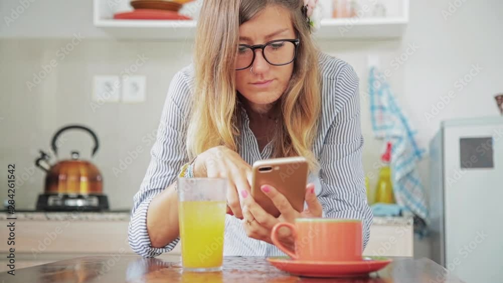 Woman using cellphone inside house and drinking coffee / tea.