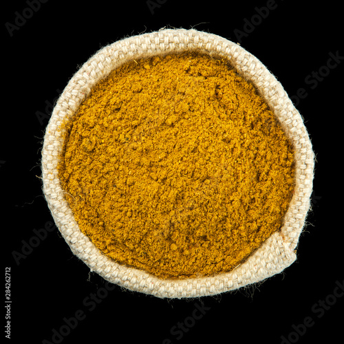Turmeric powder in a bag isolated on a black background. View from above. Seasoning on isolate. Dry spices.