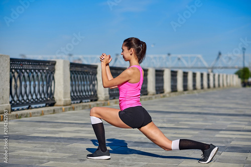 Fitness young woman stretching legs after run. outdoors sport portrait
