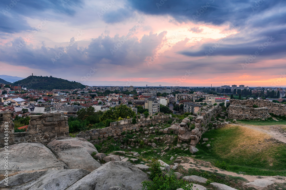 Part of ancient fortress wall on top of the Nebet tepe Hill in Plovdiv city, Bulgaria. Panoramic view with warm sunset. Summer day. Ancient Plovdiv is UNESCO's World Heritage.