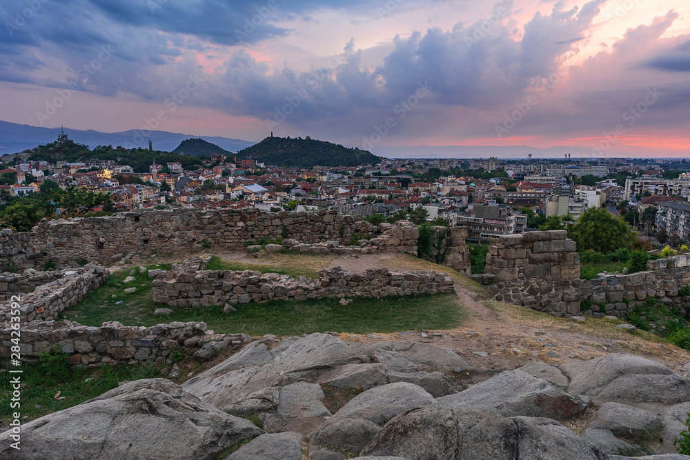 Part of ancient fortress wall on top of the Nebet tepe Hill in Plovdiv city, Bulgaria. Panoramic view with warm sunset. Summer day. Ancient Plovdiv is UNESCO's World Heritage.