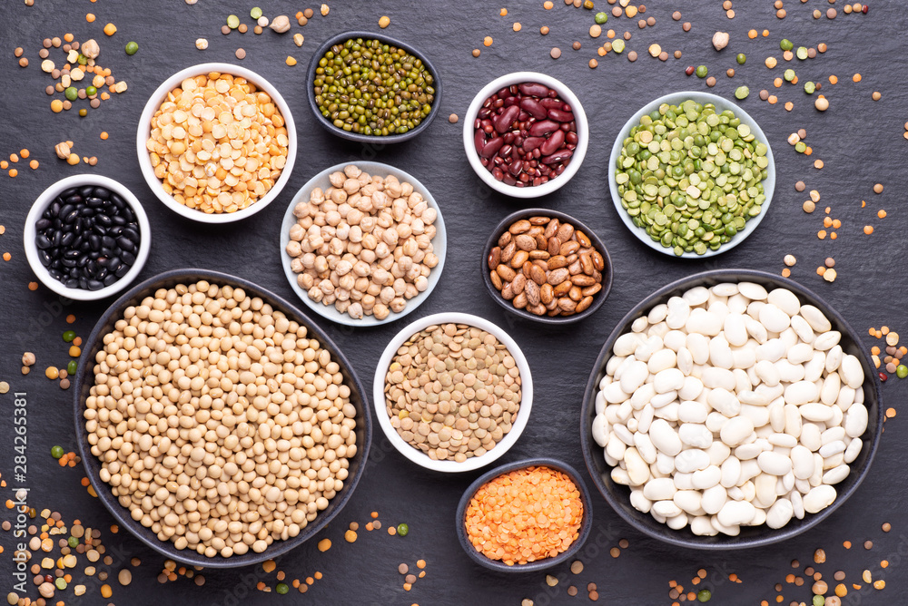 Legumes, lentils, chickpeas and beans assortment in various bowls on black stone background, top view Legumes, lentils, chickpeas and beans assortment in various bowls on black stone background, top view