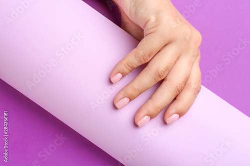 Female hand with beautiful manicure and paper on color background