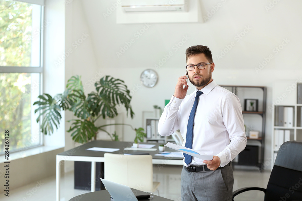 Portrait of businessman talking by phone in office Portrait of businessman talking by phone in office