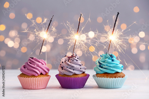 Canvas Print Tasty Birthday cupcakes on table against defocused lights