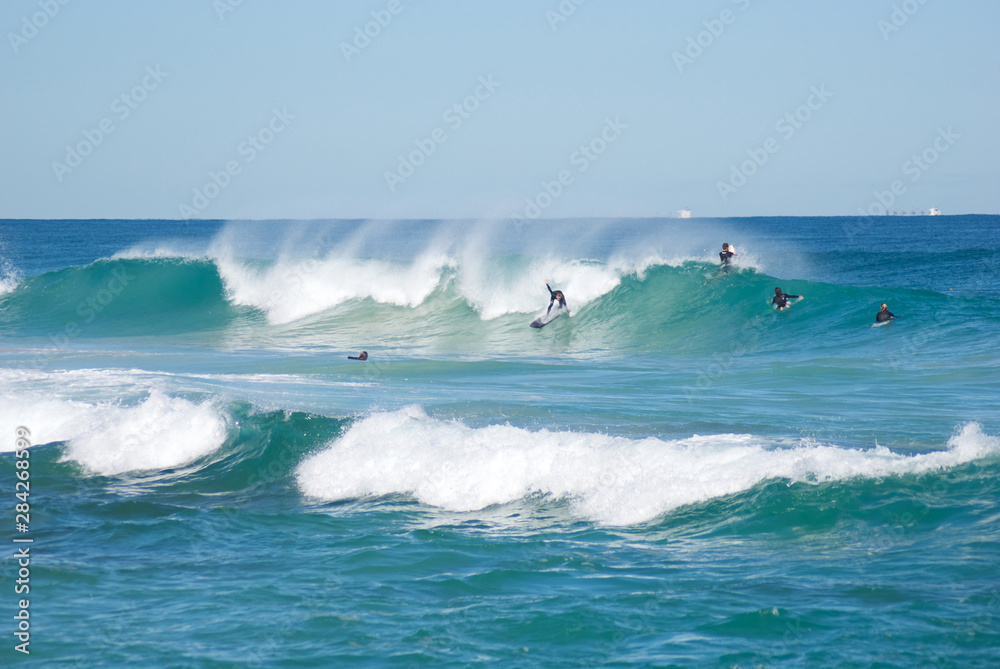 Fototapeta premium Surfers on clear cold winter morning at Trigg Beach Western Australia