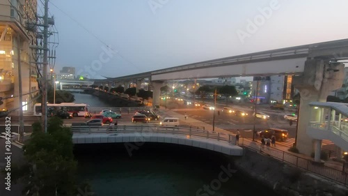 Timelapse. Naha City intersection in evening peak hour traffic. Trains travel along monorail line. photo