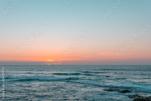 Fototapeta Naklejka Na Ścianę i Meble -  Sunset above sea or ocean. Wavy surface of water. Horizon line. Teal and orange colors concept