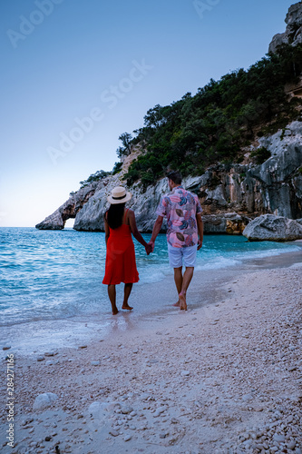 The beautiful bay in the Gulf of Orosei, Sardinia , couple during evening golden hour on the beach of Sardinia, men and woman on vacation in Italy  photo