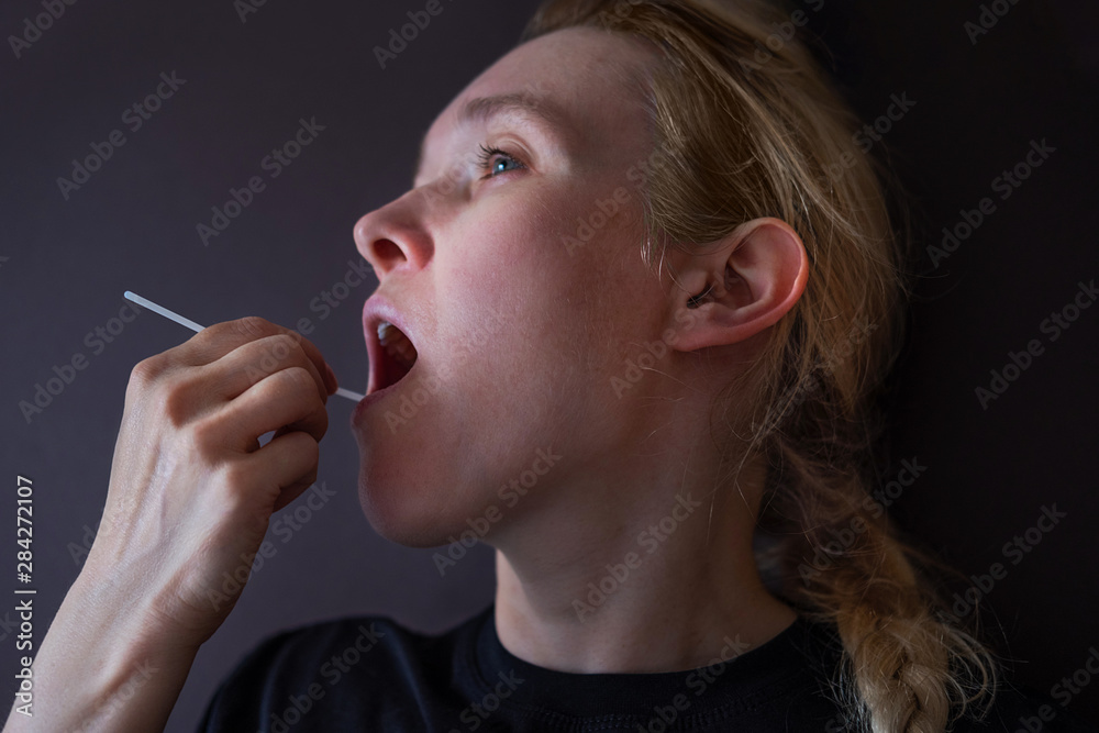 Fototapeta premium Woman doing DNA test with cotton swab at home. Test for home use