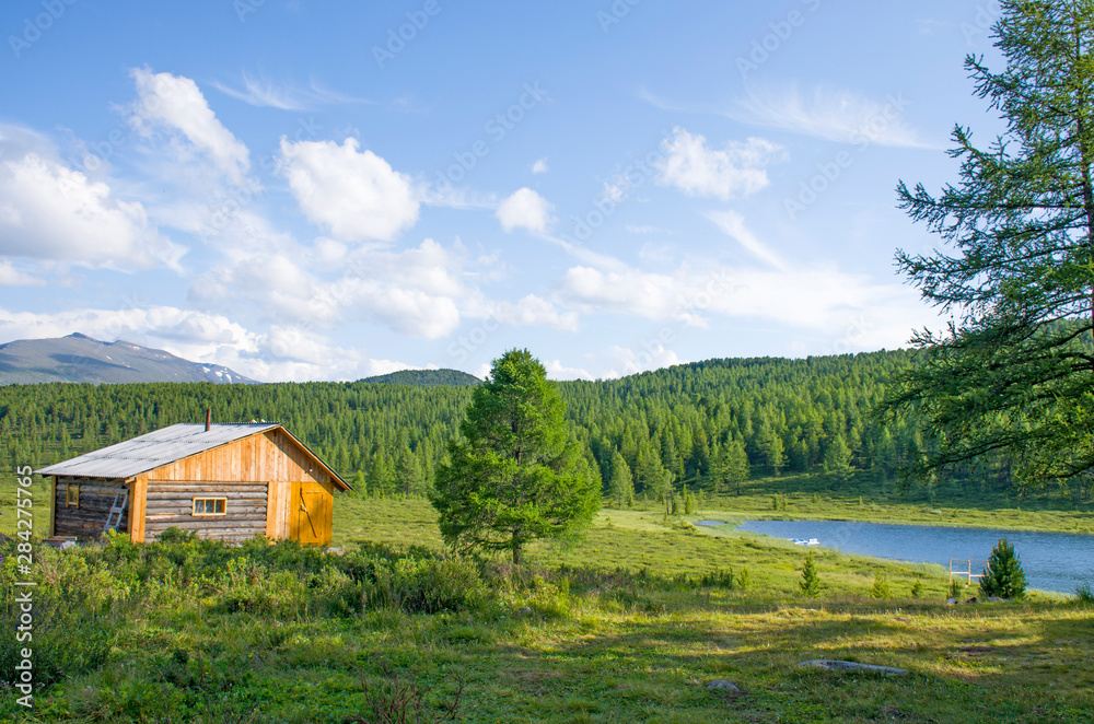House for rest in taiga against the background of the high mountains of Altai in Russia