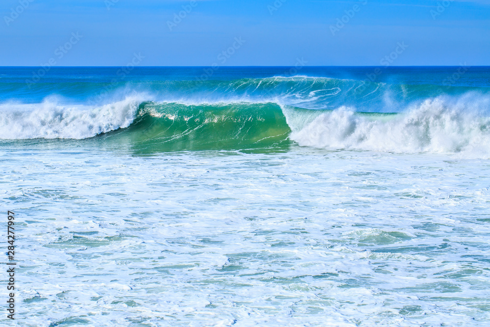 Fototapeta premium A huge waves on the ocean coast in a shine bright light at sunny day. Wonderful romantic seascape of ocean coastline.