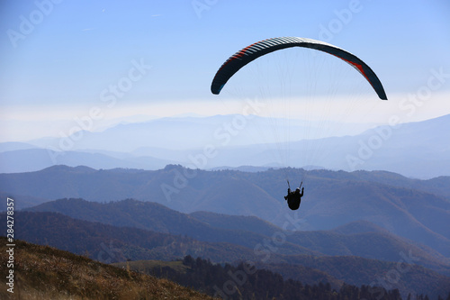 flying paraglider over valley in mountains