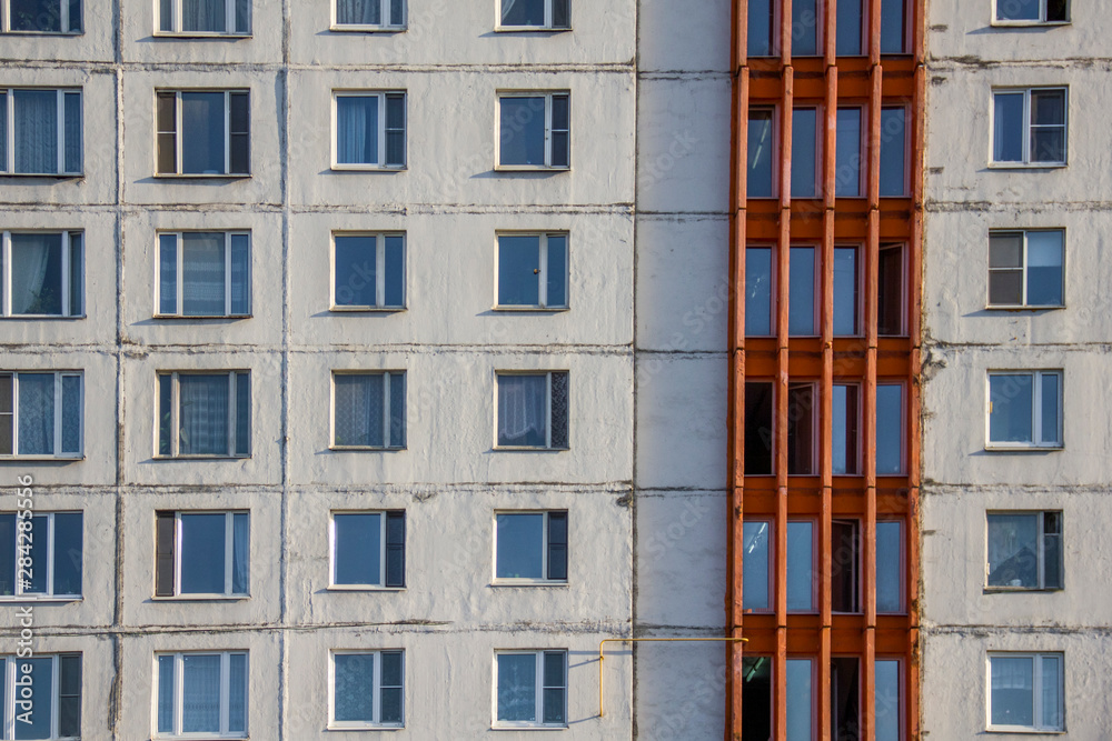facade of an old shabby high-rise building with square windows