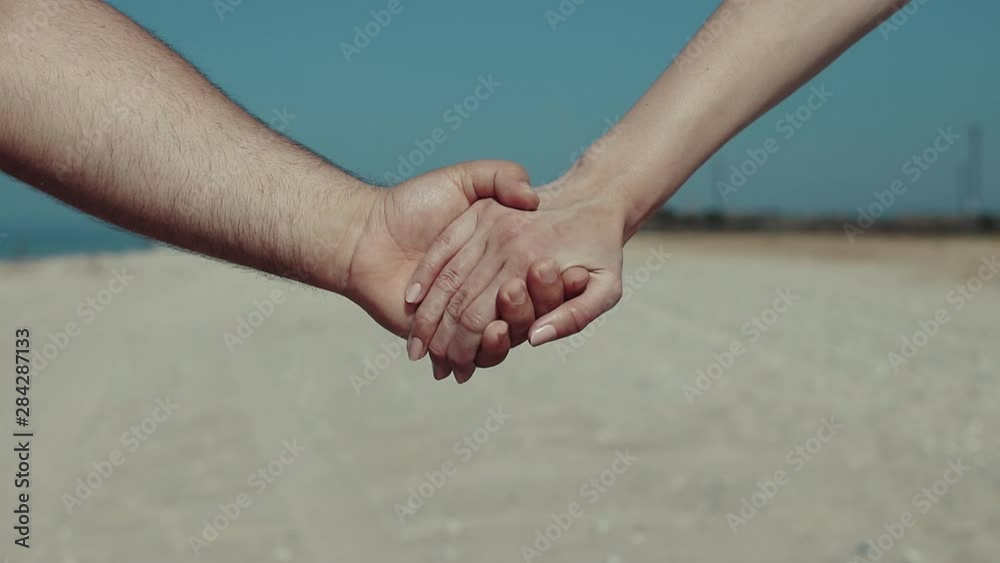 Close up of beautiful couple in love with hands joining together on the beach. romantic moment between to lovers Close up of beautiful couple in love with hands joining together on the beach. romantic moment between to lovers