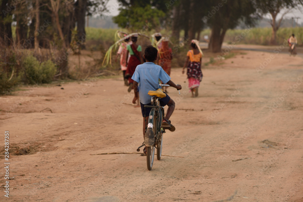 Fototapeta premium Kid riding a bike on a dirt road in a village