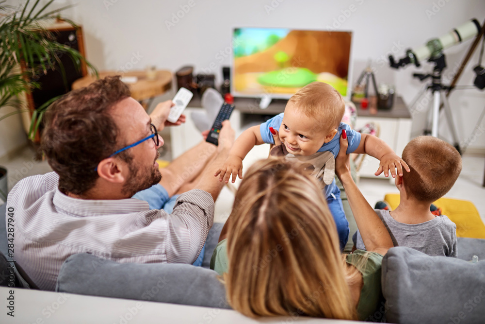 Young parents watching TV with baby boys.