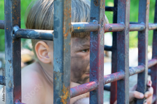 This image calls for the protection of human rights. 5 year old caucasian boy is sitting behind bars.