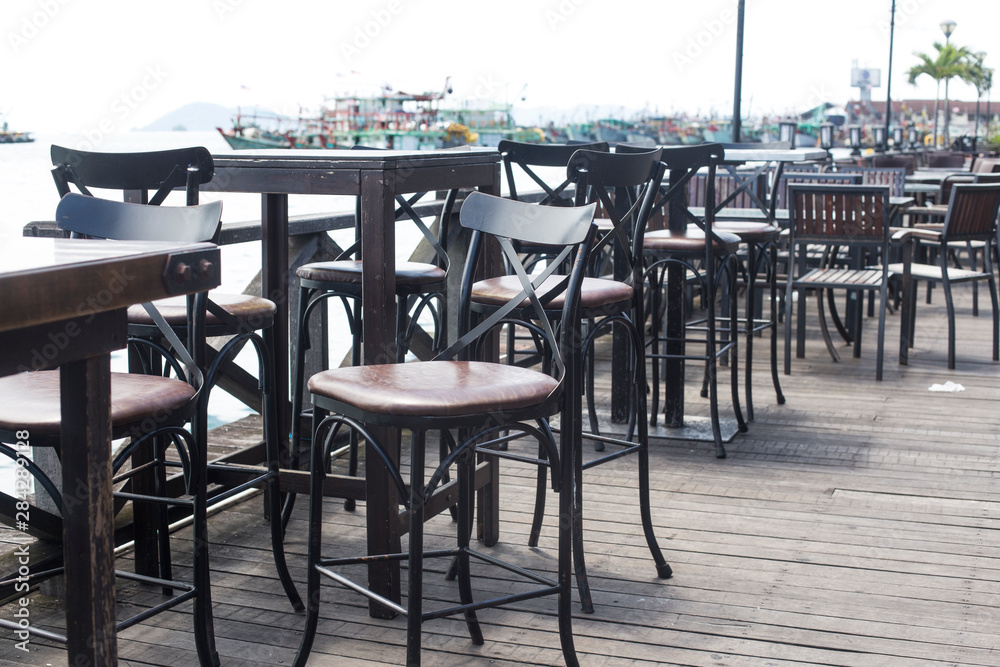 Beach cafe with wooden tables and chairs placed at the sea waterfront