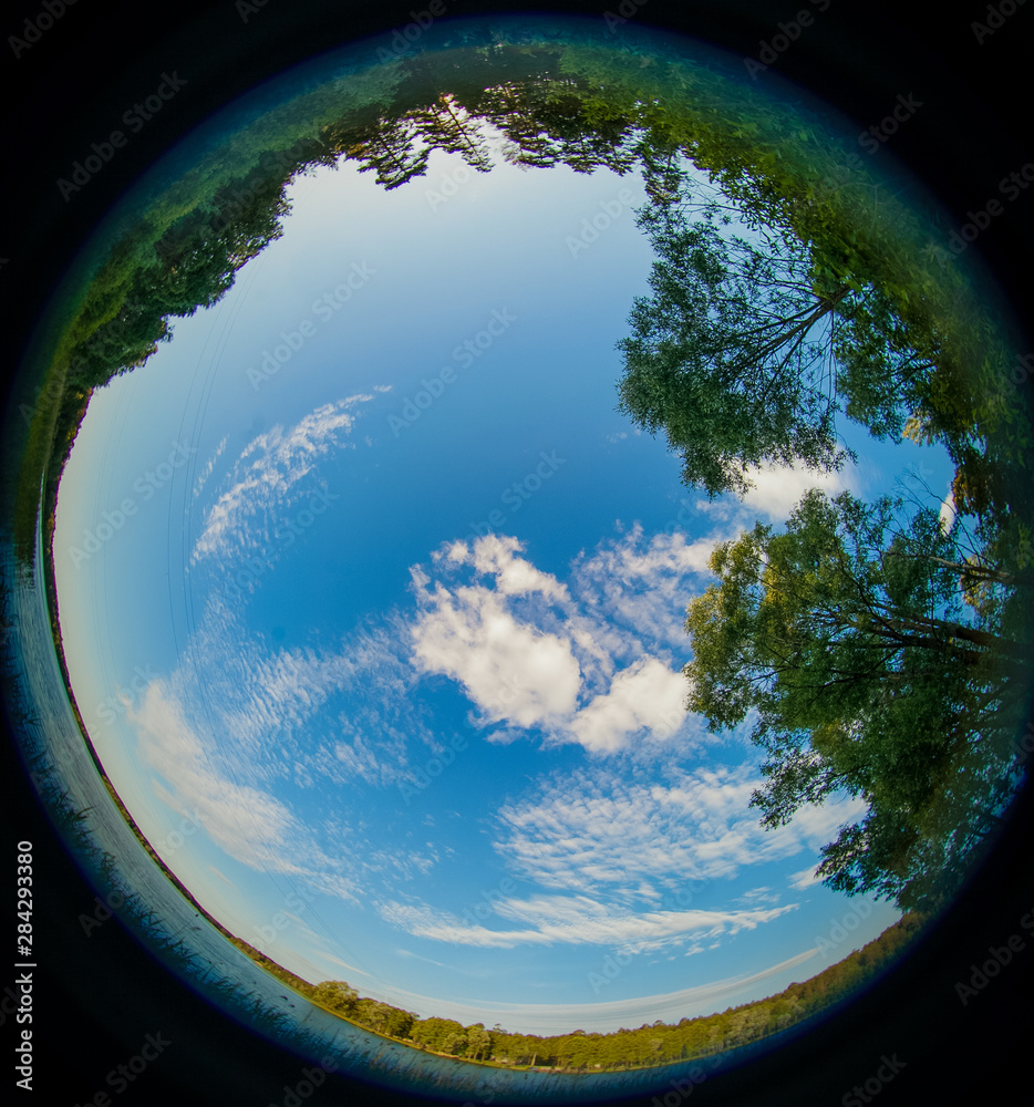 Obraz premium A fisheye view of Russian nature, blue lake and green grass with sunny sky