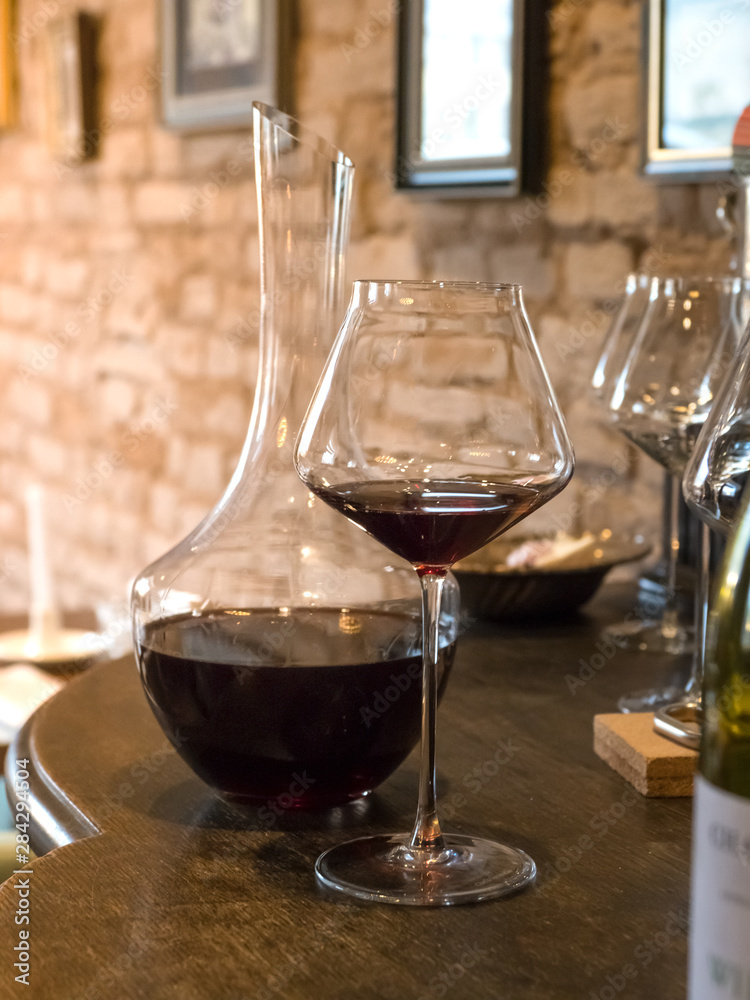 Naklejka premium Decanting old wine. Red wine in a glass on the bar