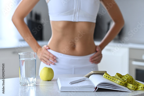 The concept of weight loss, slim girl in white kitchen counting calories