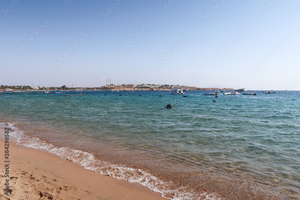 Sharm el-Sheikh, Egypt - November 11, 2017: Naama Bay sea beach in Sharm el-Sheikh, Egypt. People bathe, rest. Boats are sailing in the sea.