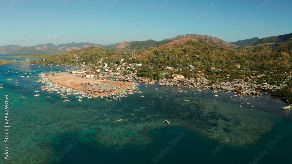 aerial view City Quay with boat dock and public market Coron town, tourist destination in the Philippines. Pier and promenade with boats on Busuanga island. Wooden boats waiting at pier. Seascape with