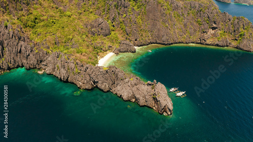 Aerial drone tropical landscape bay with beach and clear blue water surrounded by cliffs. El nido, Philippines, Palawan. Seascape with tropical rocky islands, ocean blue water. Summer and travel