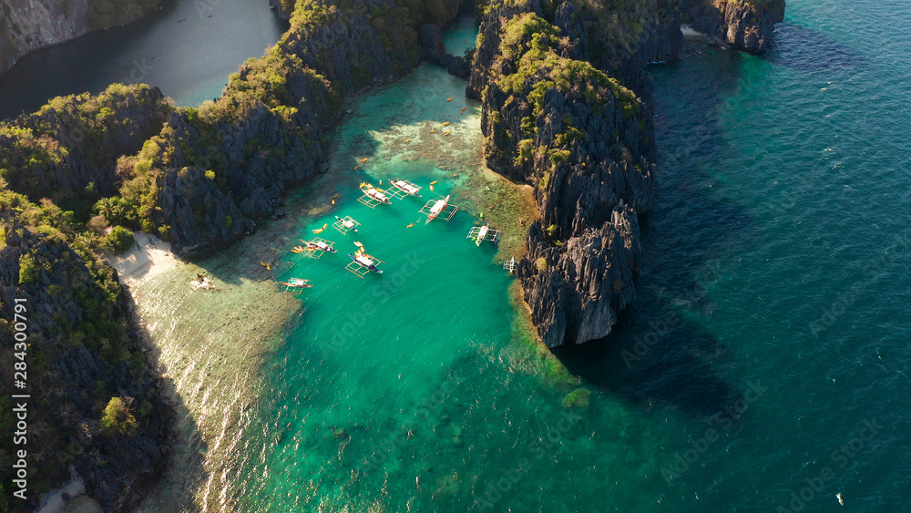 Tourist boats over tropical lagoon and coral reef, aerial view. Small lagoon with turquoise water. El nido, Philippines, Palawan. Summer and travel vacation concept.