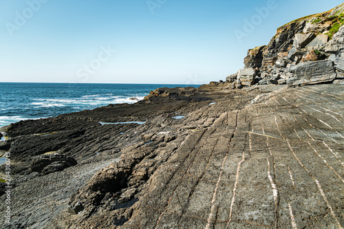 Rocky clifss with textured ground and white lines close to sea in Asturian Coast, Spain photo