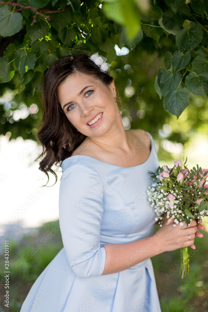 Portrait of romantic young woman with bouquet in retro dress in summer, green trees on the background Portrait of romantic young woman with bouquet in retro dress in summer, green trees on the background