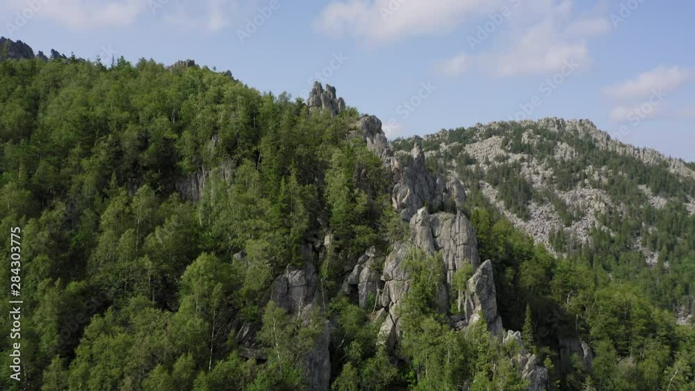 aerial view of russian natural landscape. drone flying backward near the steep stony slope with deep mixed forest at foot of mount. panoramic view of valley and mountain ranges Taganay aerial view of russian natural landscape. drone flying backward near the steep stony slope with deep mixed forest at foot of mount. panoramic view of valley and mountain ranges Taganay