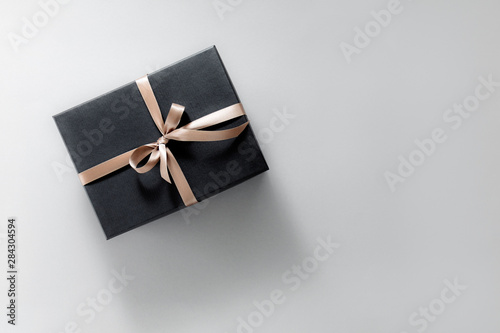 Gift wrapped in dark paper on pastel background